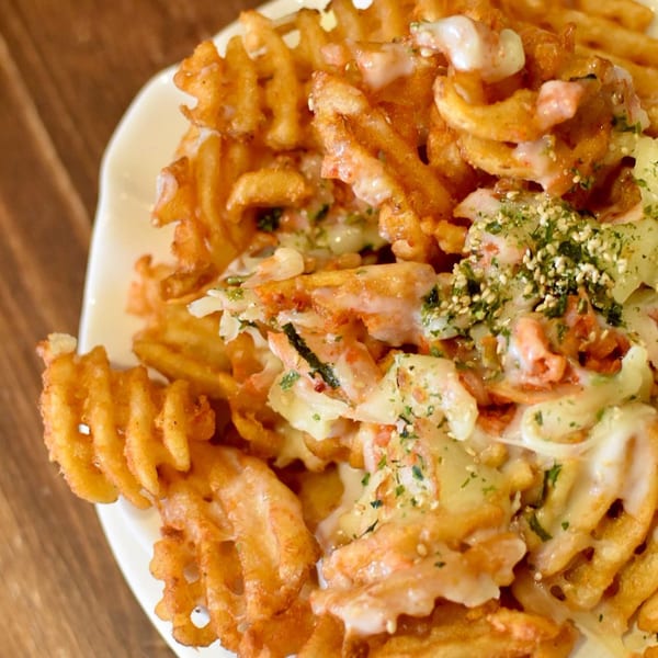 Double Chin's waffle fries topped with creamy sauce, green herbs, and sesame seeds.