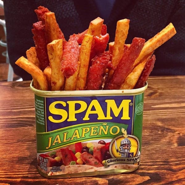 Jalapeño Spam fries and regular fries served in a Spam can on a wooden table.